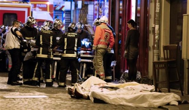 Rescue workers gather at victims in the 10th district of Paris, Friday, Nov. 13, 2015.